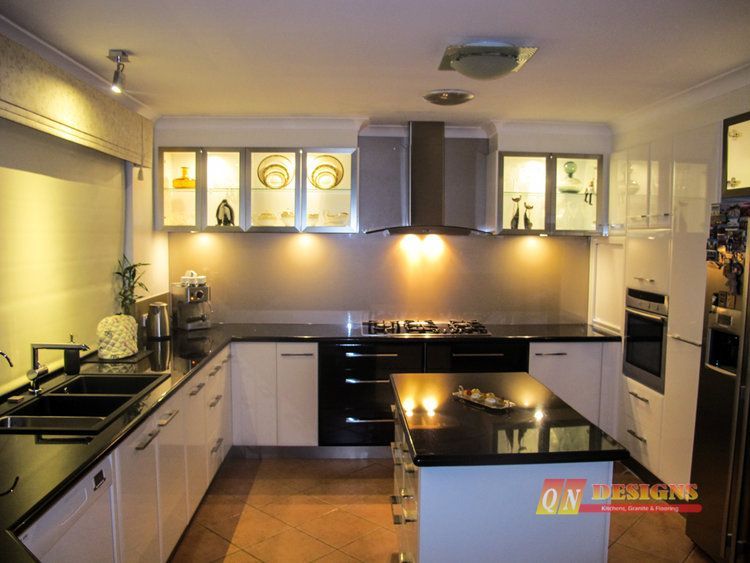 A kitchen with white cabinets black counter tops and a stove top oven