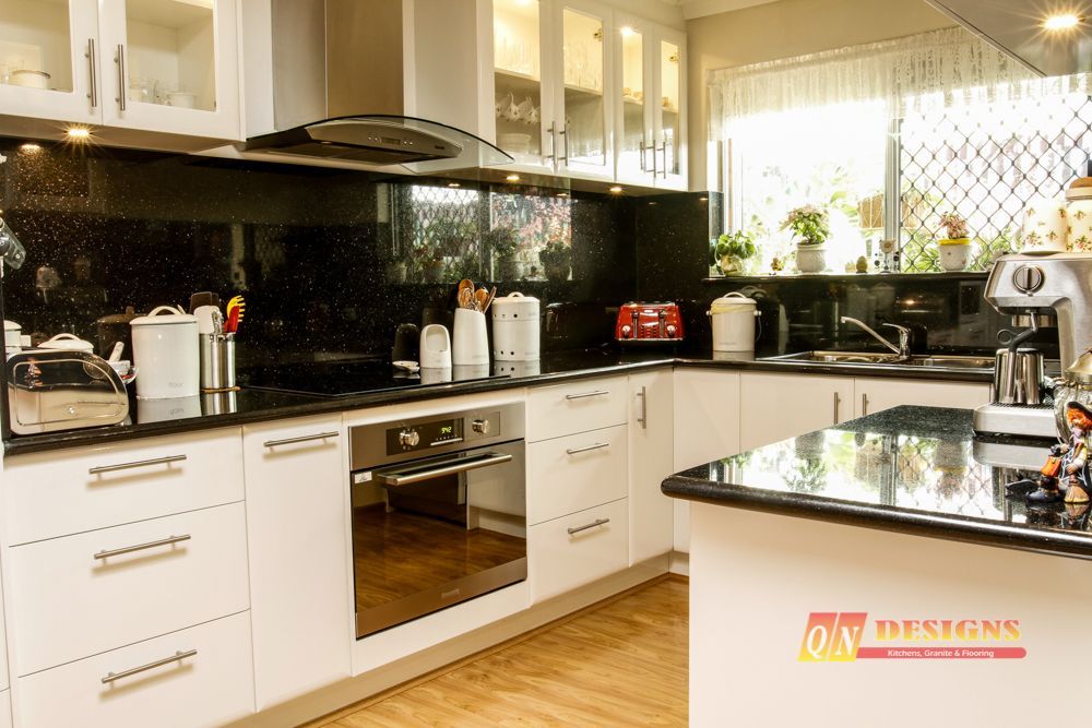 A kitchen with white cabinets and black counter tops