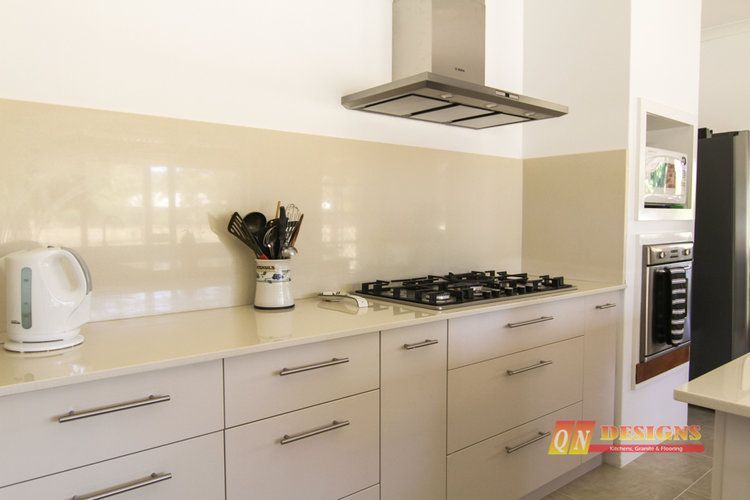 A kitchen with white cabinets and a stove top oven