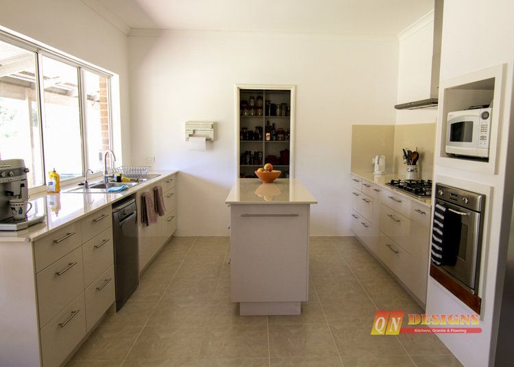 A kitchen with white cabinets and a large island in the middle