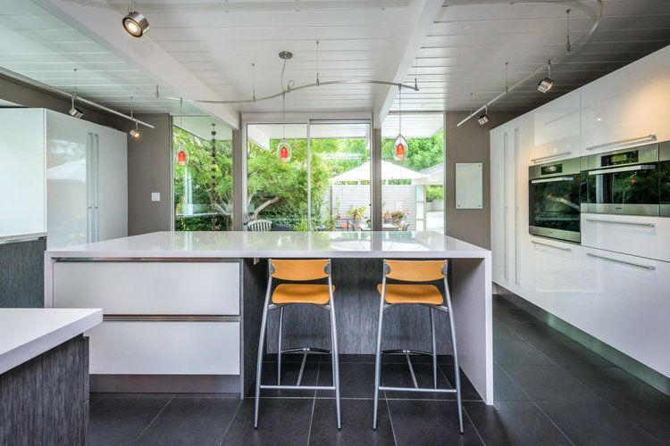 A kitchen with a large island and two yellow stools.