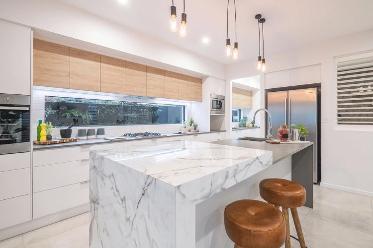 A kitchen with a marble counter top and stools