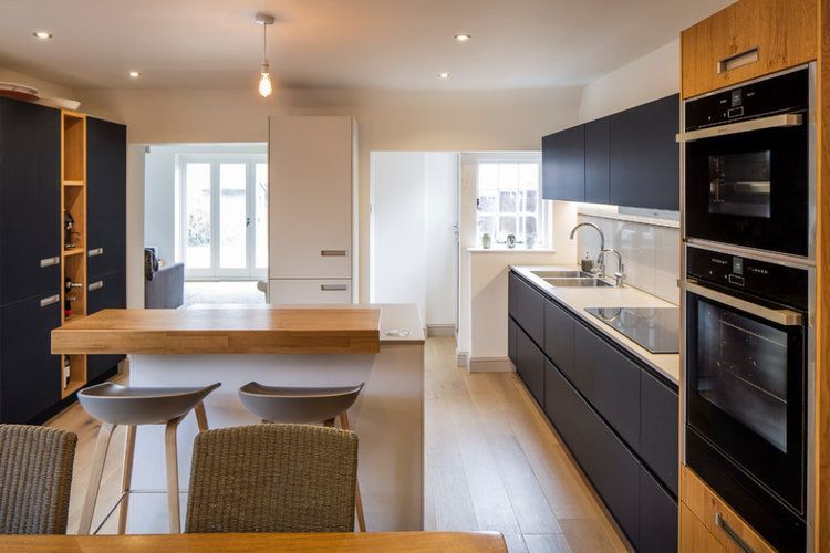 A kitchen with black cabinets and wooden floors and a table and chairs.