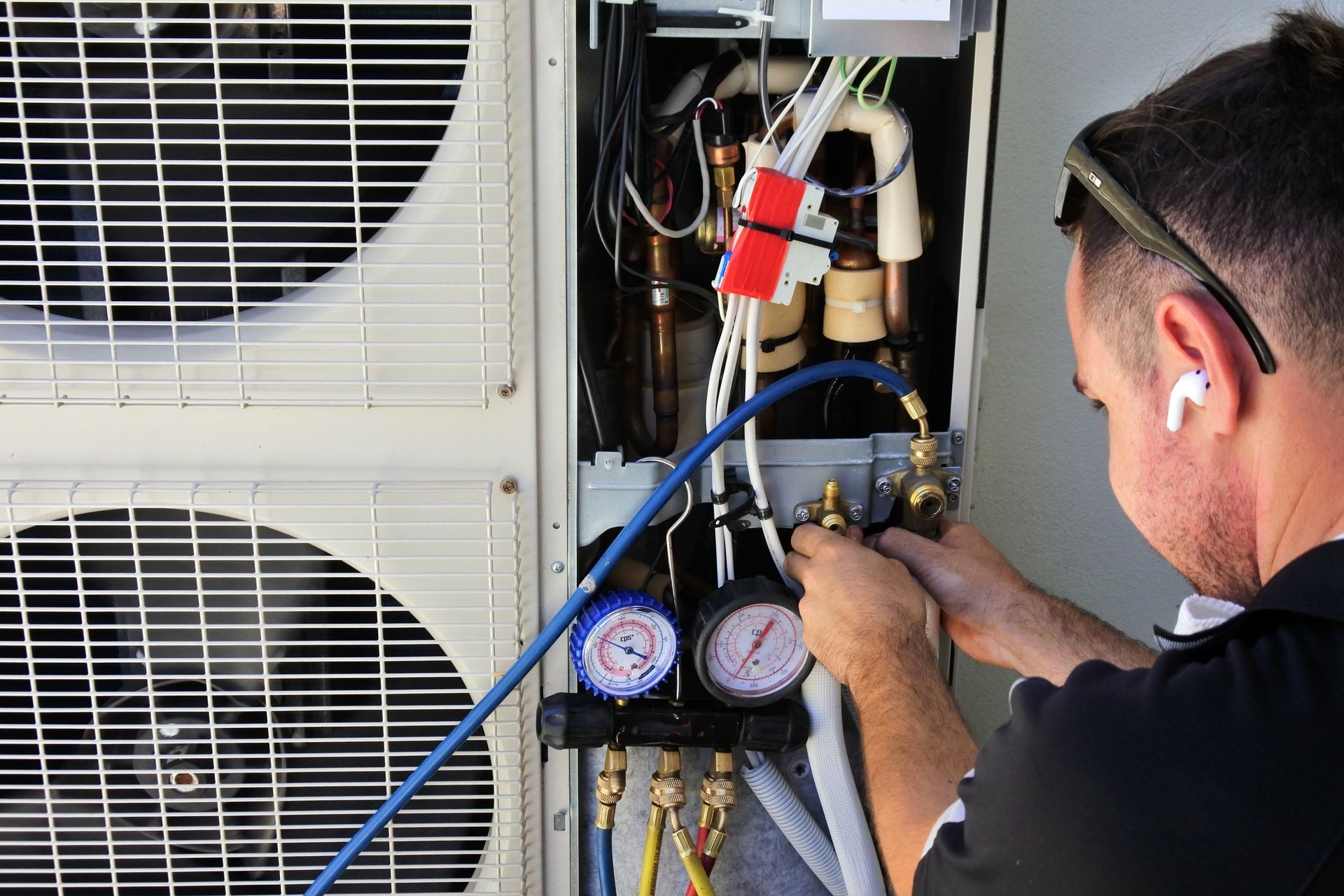 A man is working on an air conditioner outside of a building.