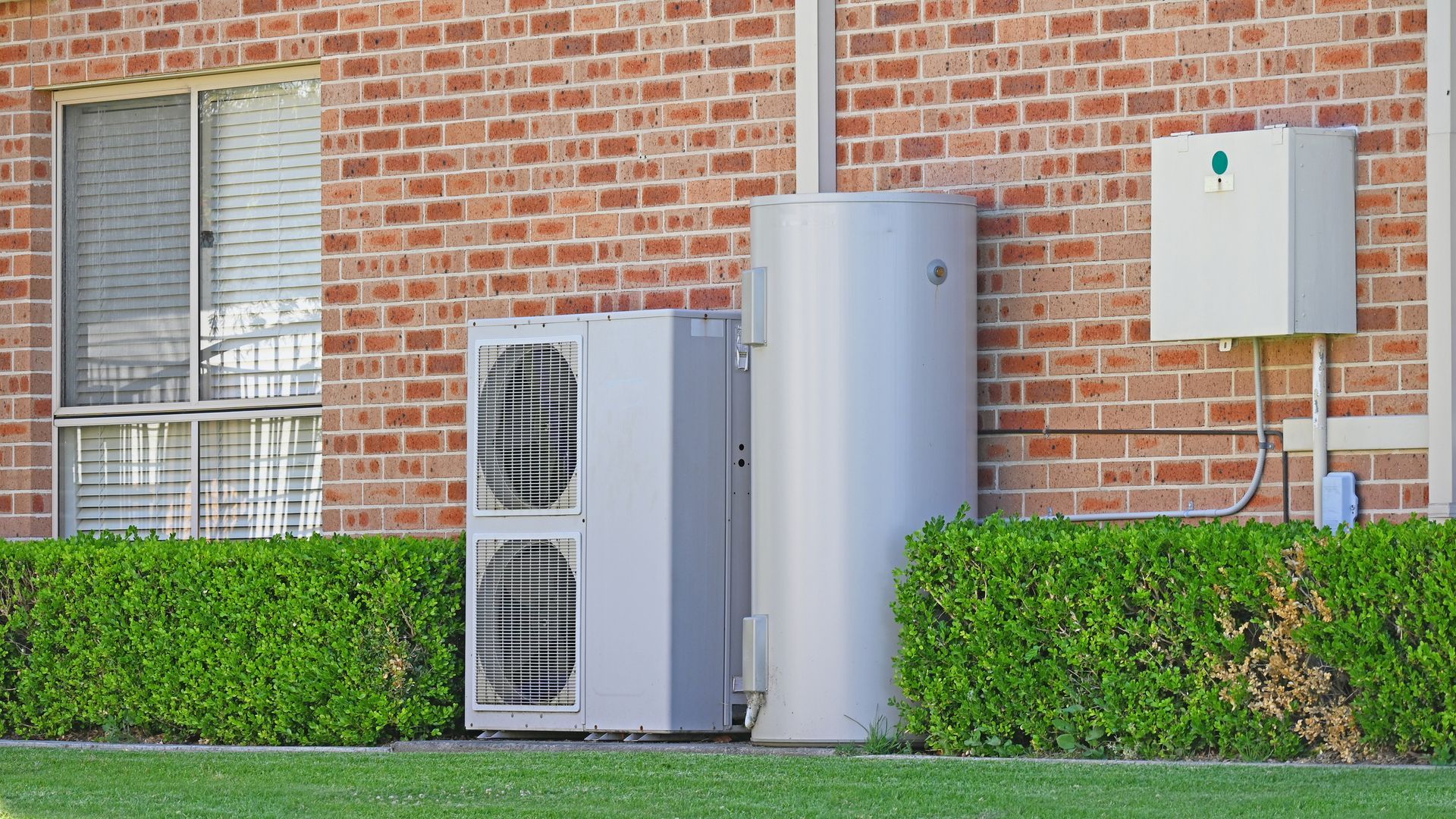 A brick building with two water heaters on the side of it.