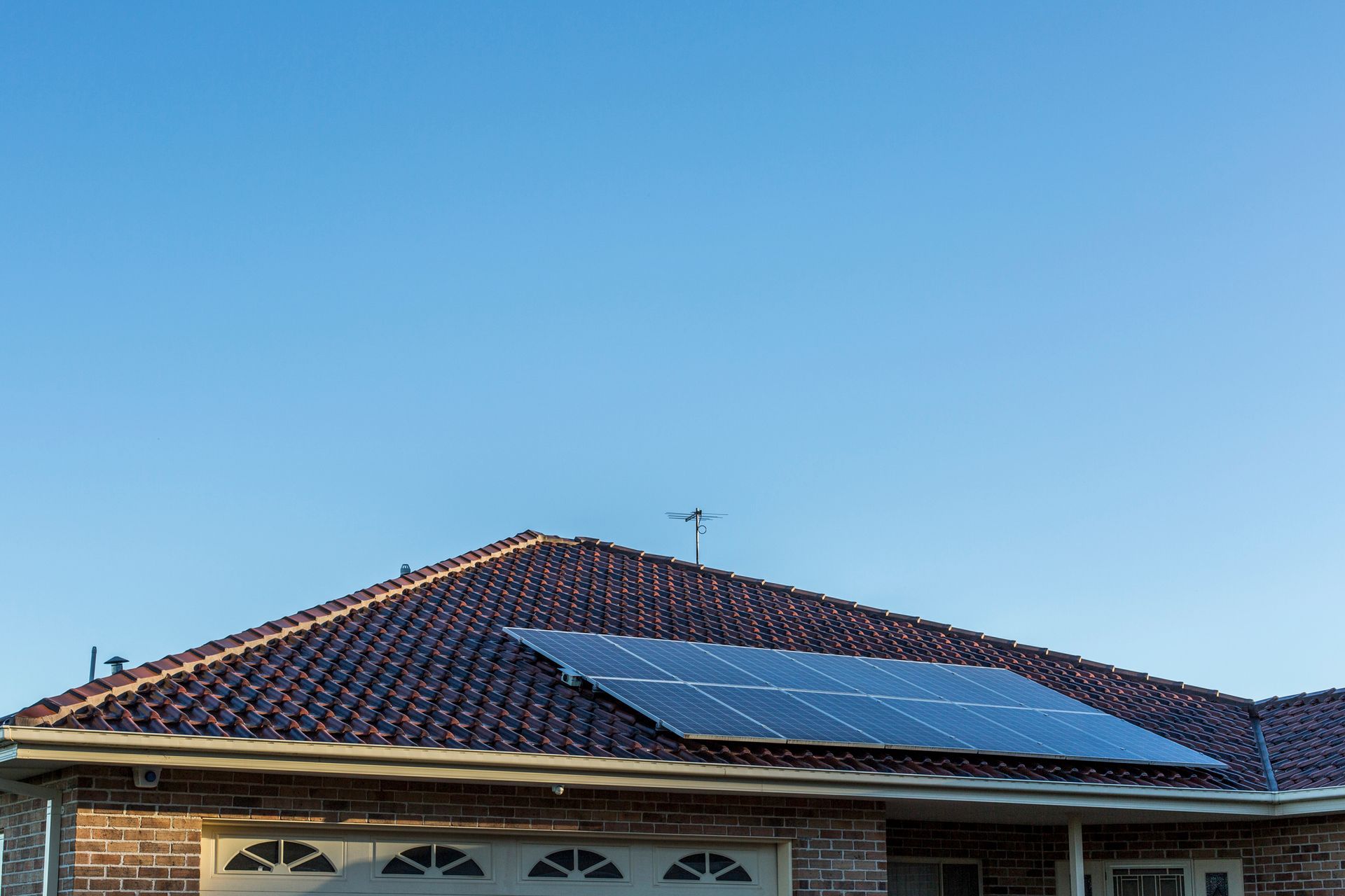 A house with solar panels on the roof and a blue sky in the background.