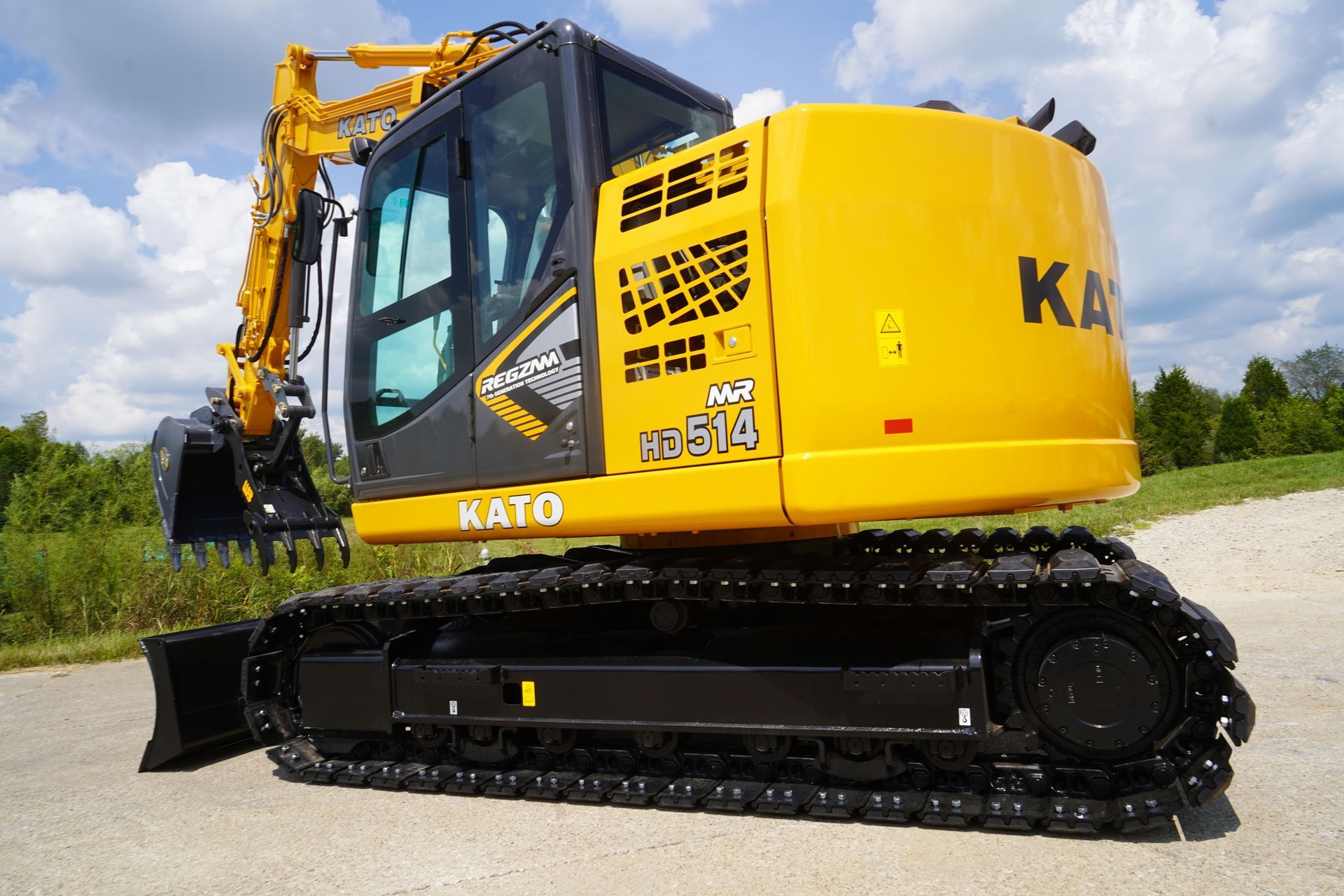 A yellow excavator with a black bucket on grey pavement