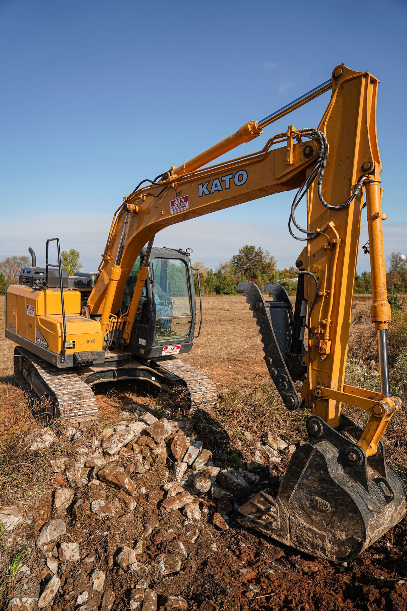 A yellow excavator with a black bucket on dirt