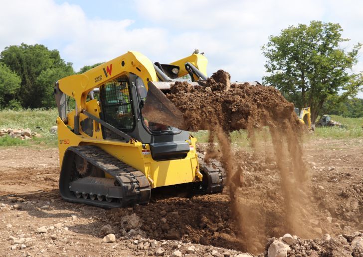 A yellow tractor with a black bucket spilling dirt 