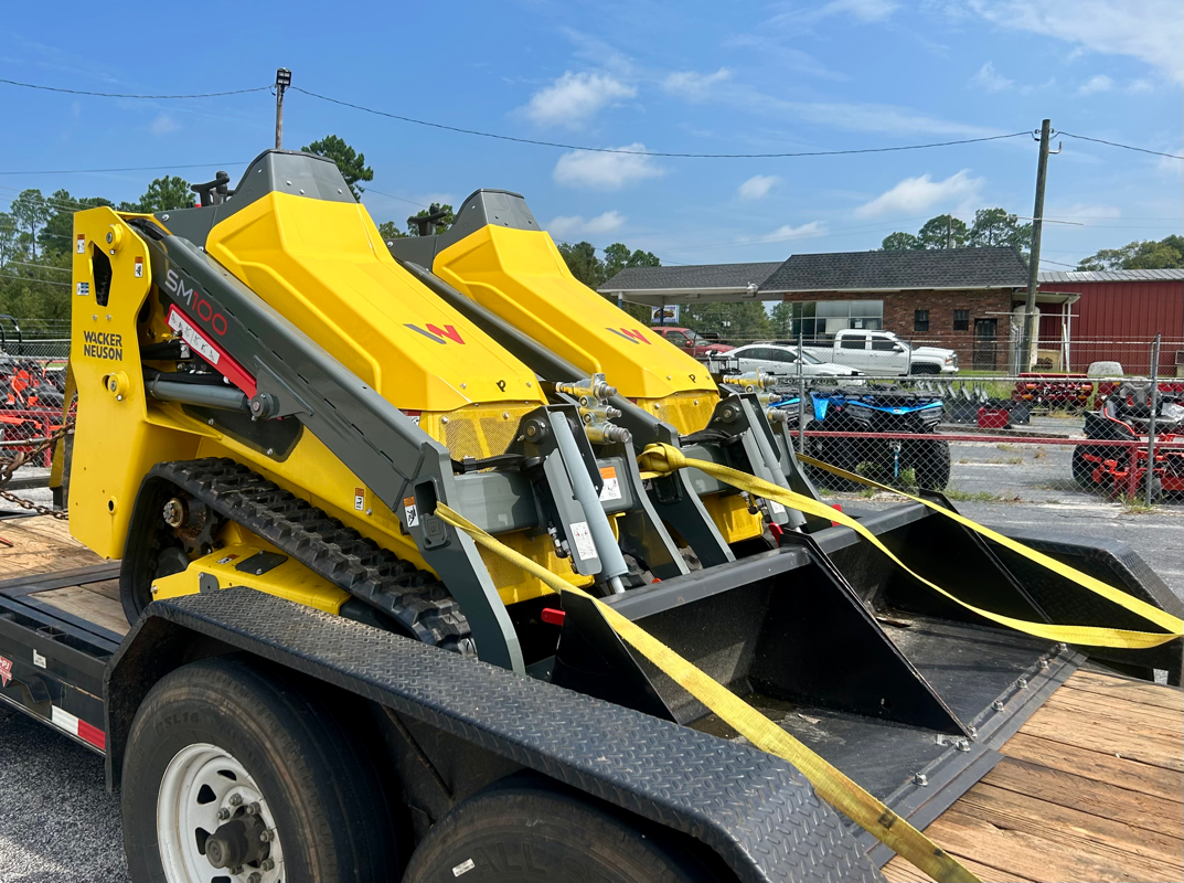 two yellow tractors with a black bucket on a black trailer 