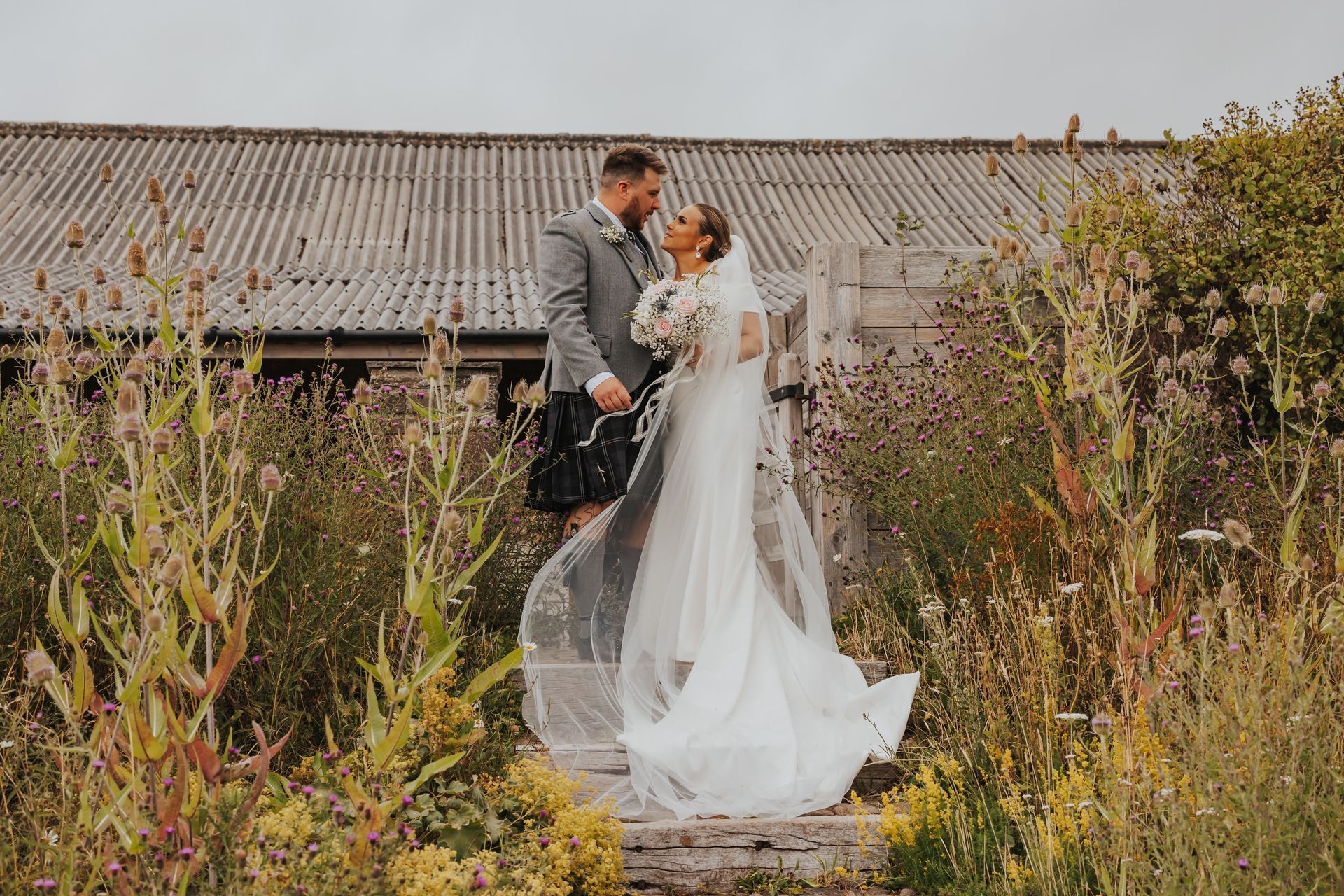 A couple stood on steps in the middle of wildflowers