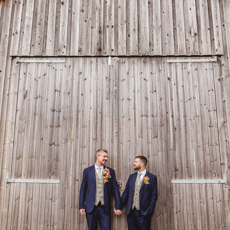 a couple stood infront of big old rustic barn doors