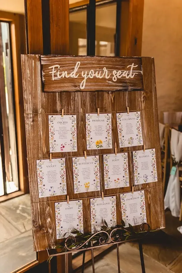 A wooden board with table names and guest names on