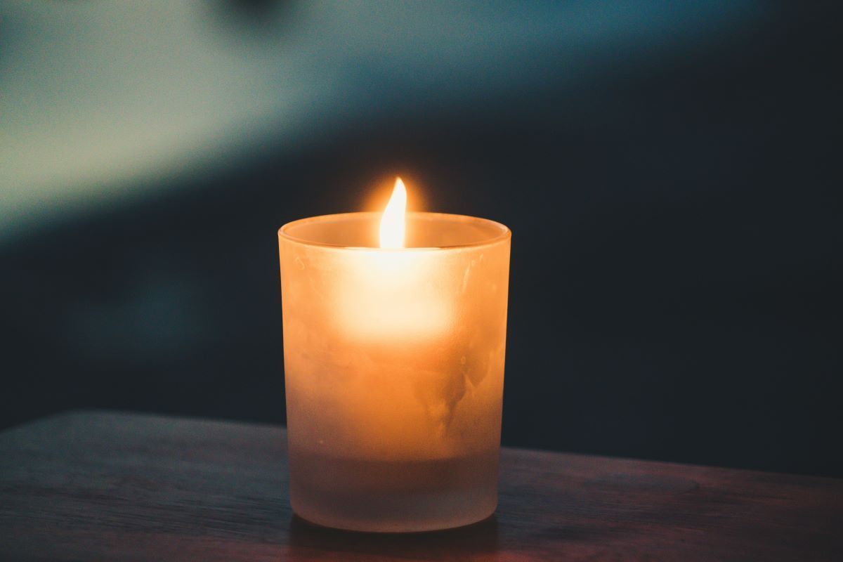 A lit candle is sitting on a wooden table next to dried berries.