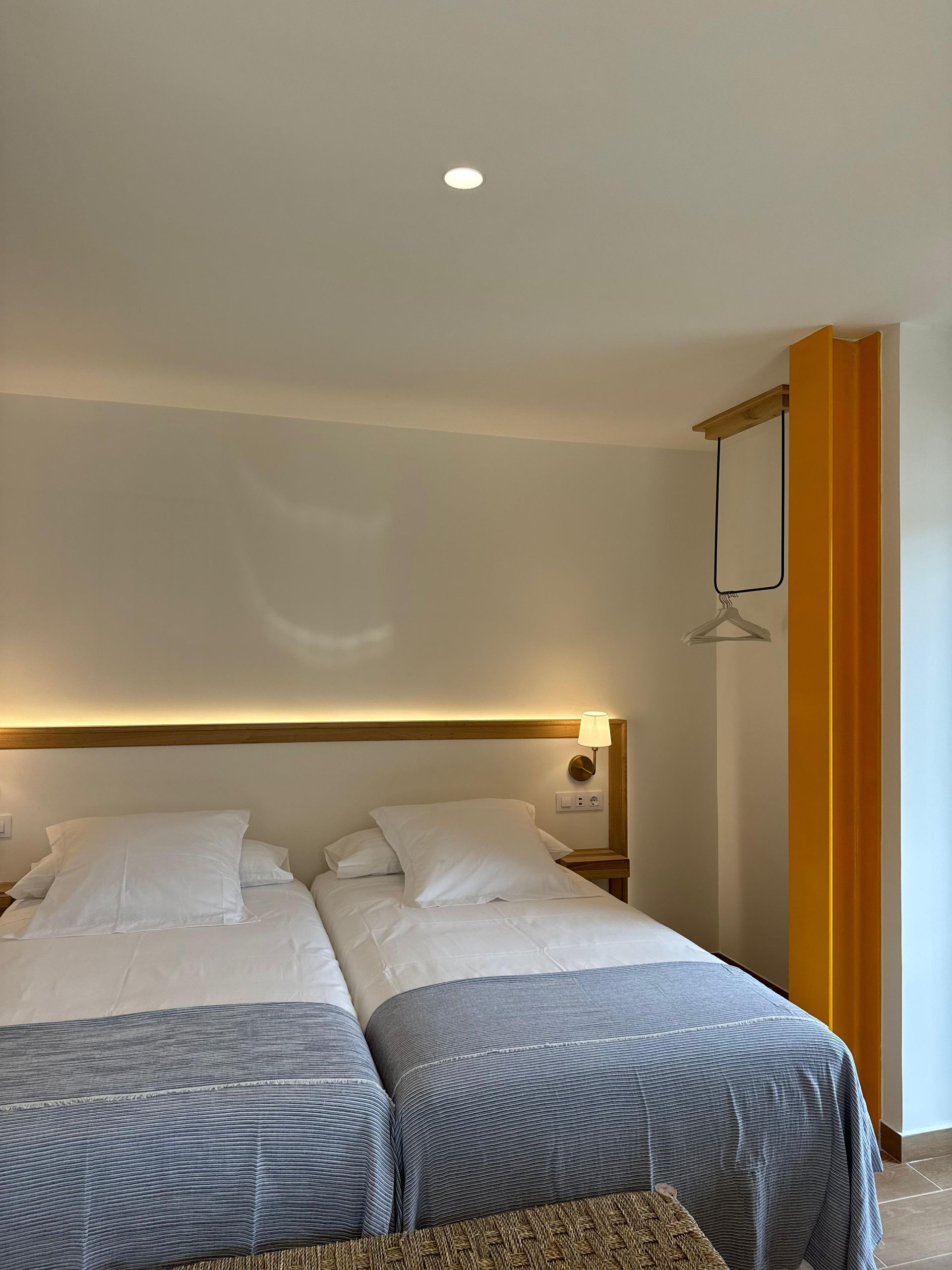 Dos camas individuales con mantas azules y blancas en una habitación con una pared amarilla.