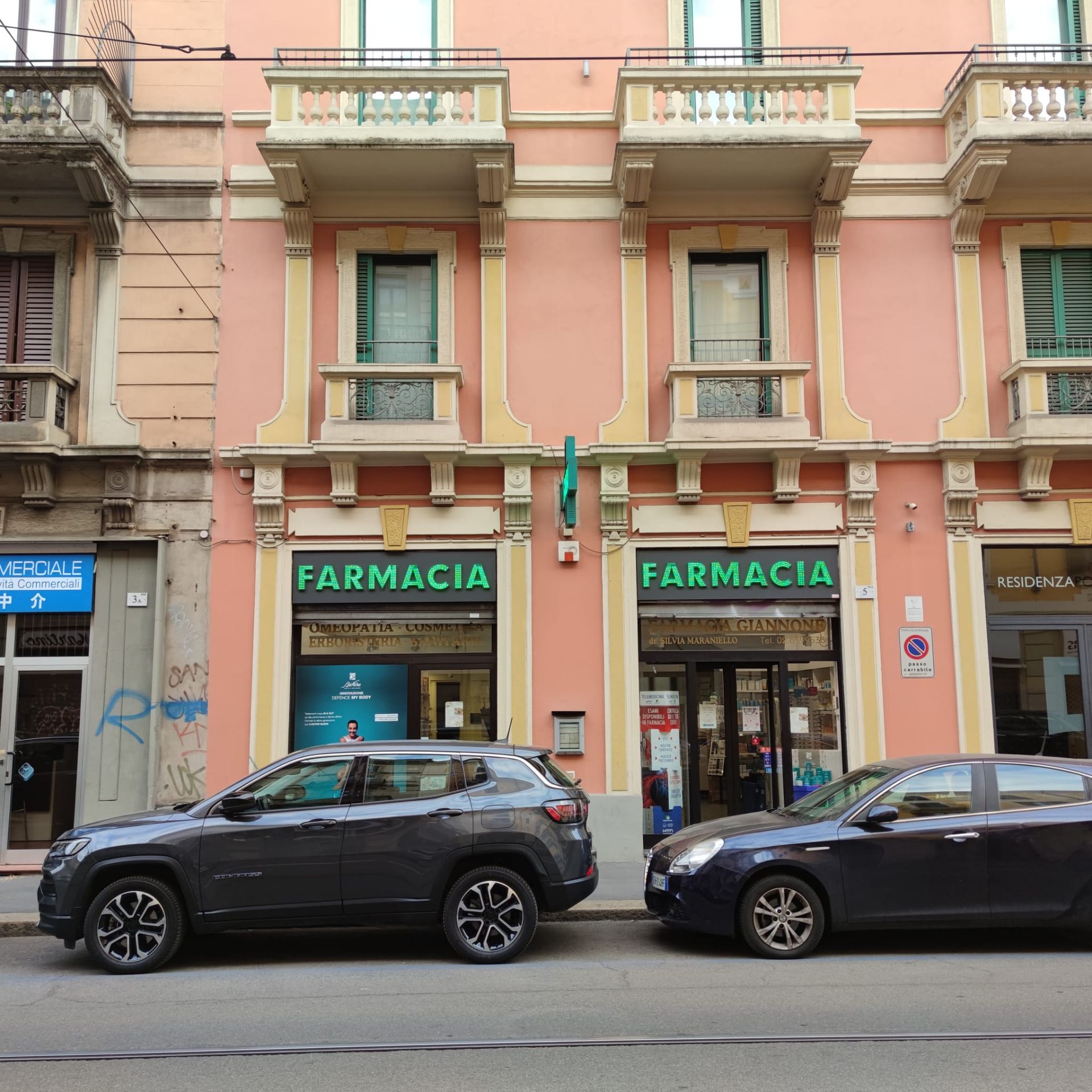 Due auto sono parcheggiate davanti a un edificio con la scritta farmacia