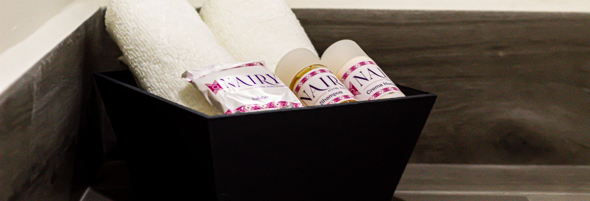 Una cesta negra llena de toallas y jabón en el mostrador del baño.