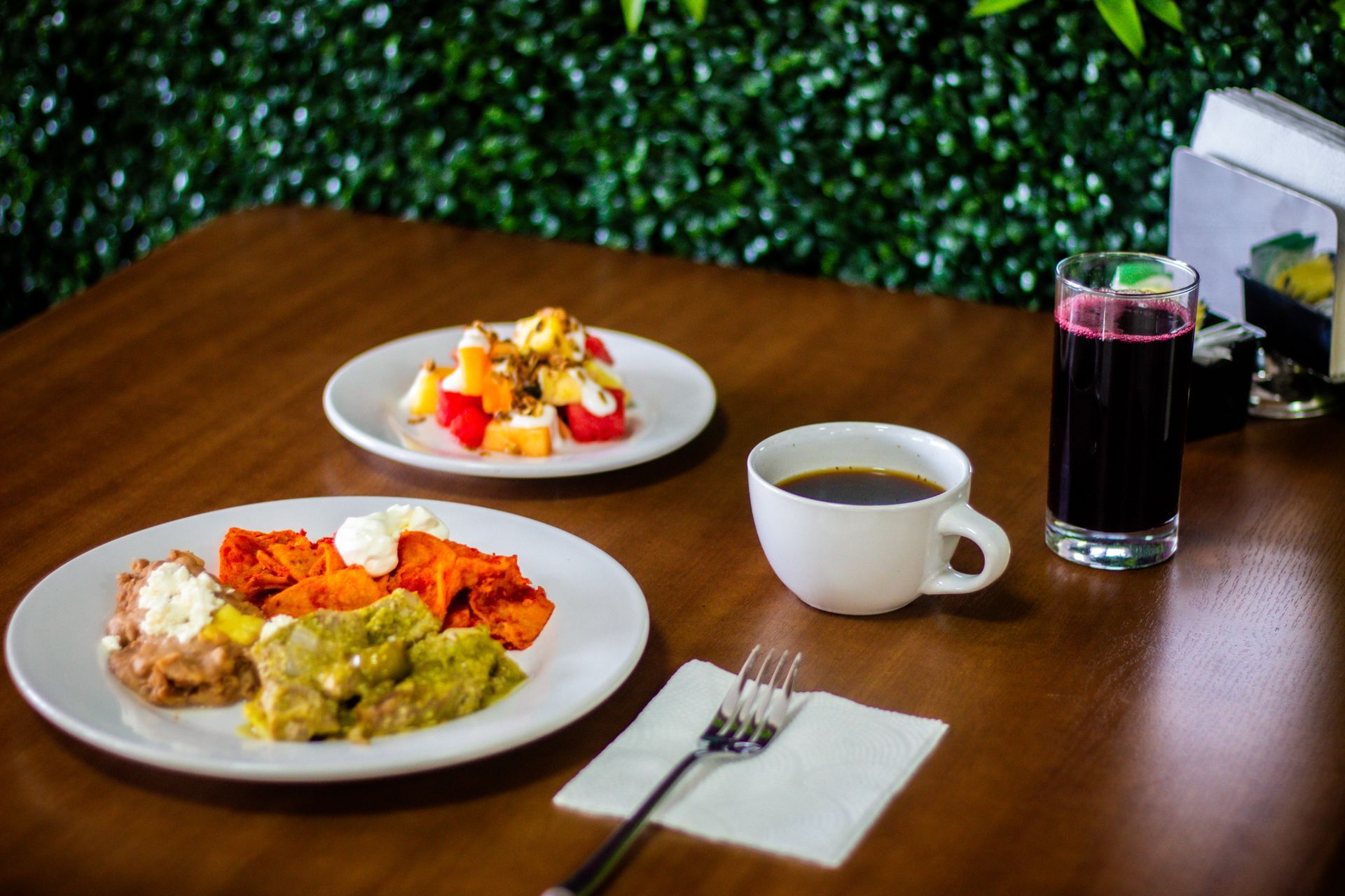 Una mesa de madera cubierta con platos de comida y una taza de café.