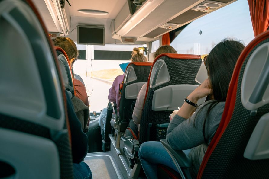 Passeggeri seduti su un autobus, visti di spalle mentre guardano verso la parte anteriore.