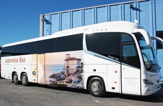 REAR LATERAL VIEW OF A BUS WITH A BUILDING IN THE BACKGROUND