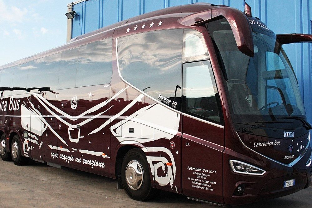 Vista lateral de un autobús fucsia con el dibujo de un monumento