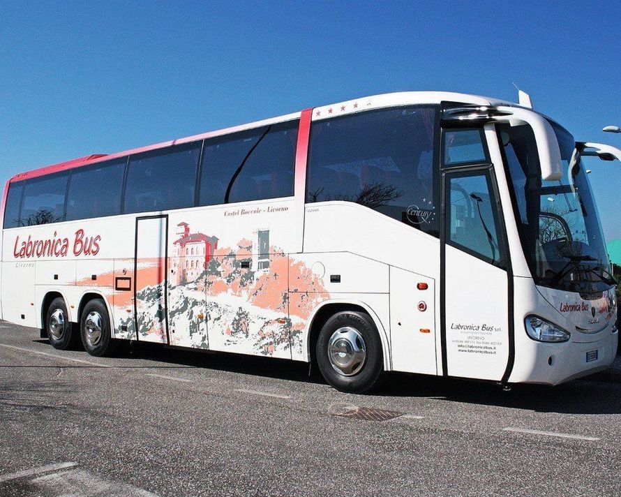 Un autobus Labronica bianco e rosso parcheggiato su una superficie asfaltata sotto un cielo azzurro e limpido.