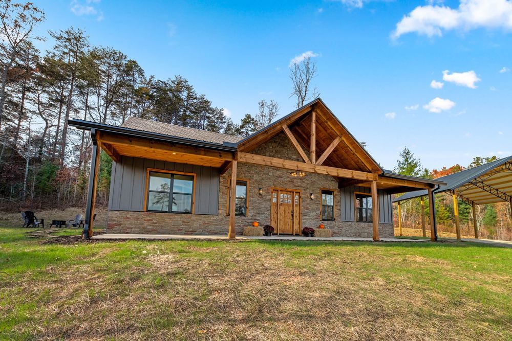 A large house with a lot of windows is sitting in the middle of a lush green field.