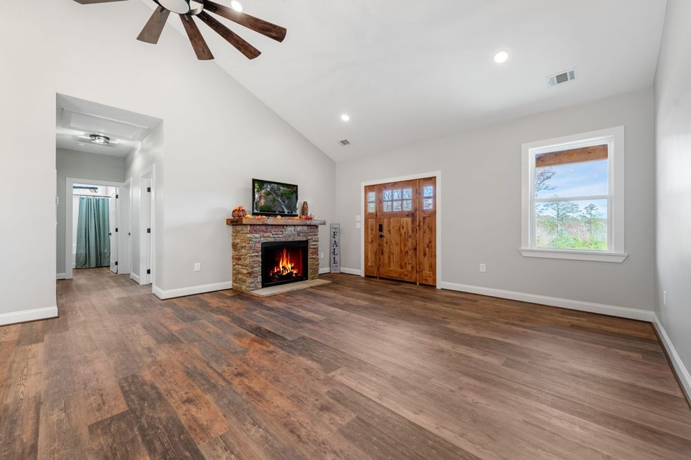 A living room with hardwood floors , a fireplace and a ceiling fan.