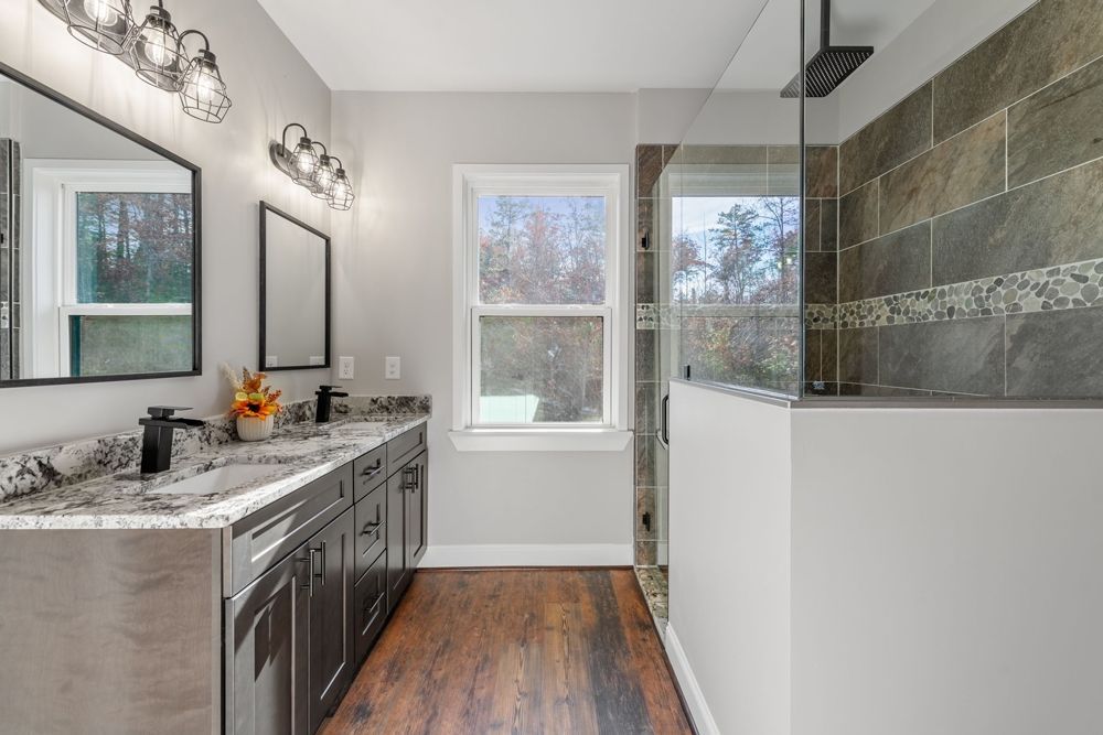 A bathroom with two sinks and a walk in shower.
