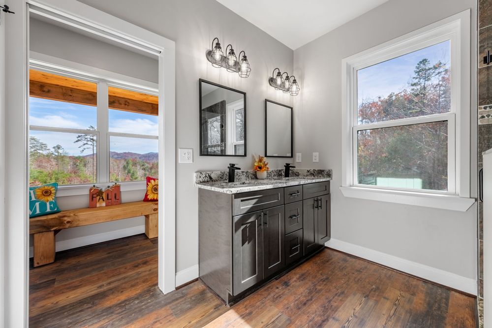 A bathroom with two sinks , two mirrors and a bench.