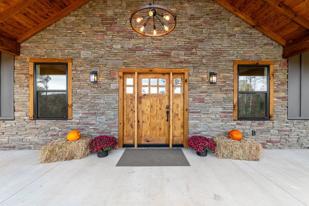 The front door of a house with a wooden door and a stone wall.