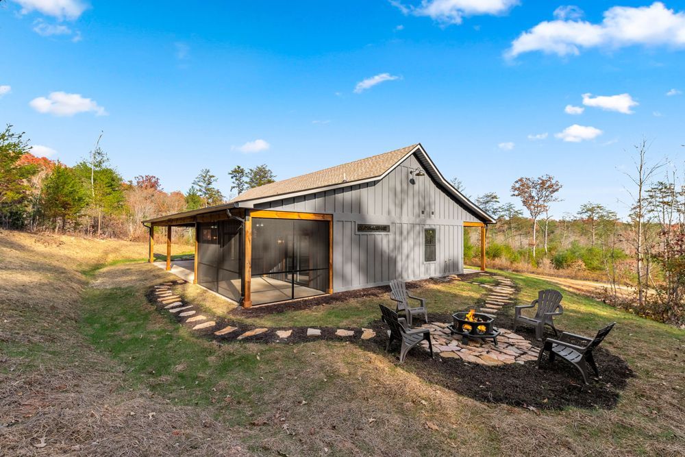 A small house with a screened in porch and a fire pit in front of it.