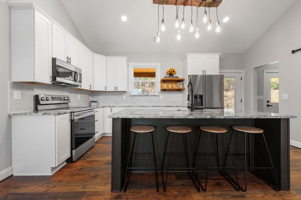 A kitchen with white cabinets , stainless steel appliances , and a large island.