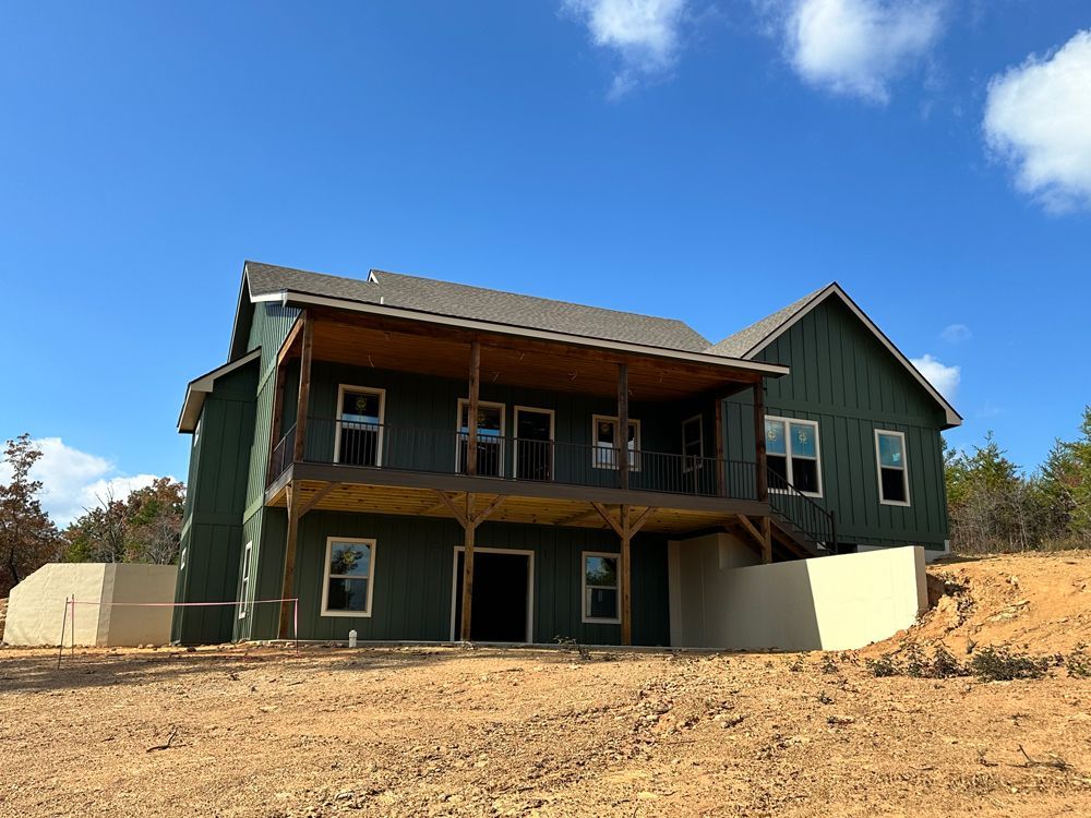 A large green house is sitting on top of a dirt hill.