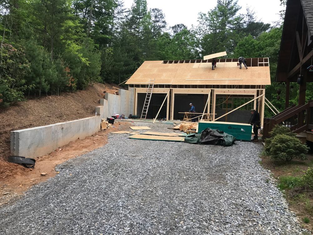 A garage is being built on a hill with a gravel driveway leading to it.