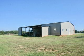 A large barn is sitting in the middle of a grassy field.