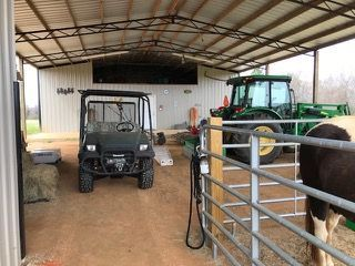 A tractor and a golf cart are parked in a barn.