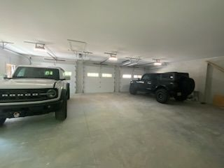 Two cars are parked in a garage next to each other.