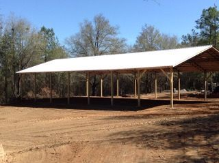 A large covered area with a white roof in the middle of a dirt field.
