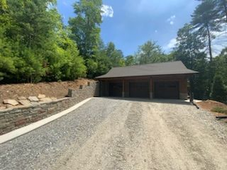 A garage with a driveway leading to it is surrounded by trees.