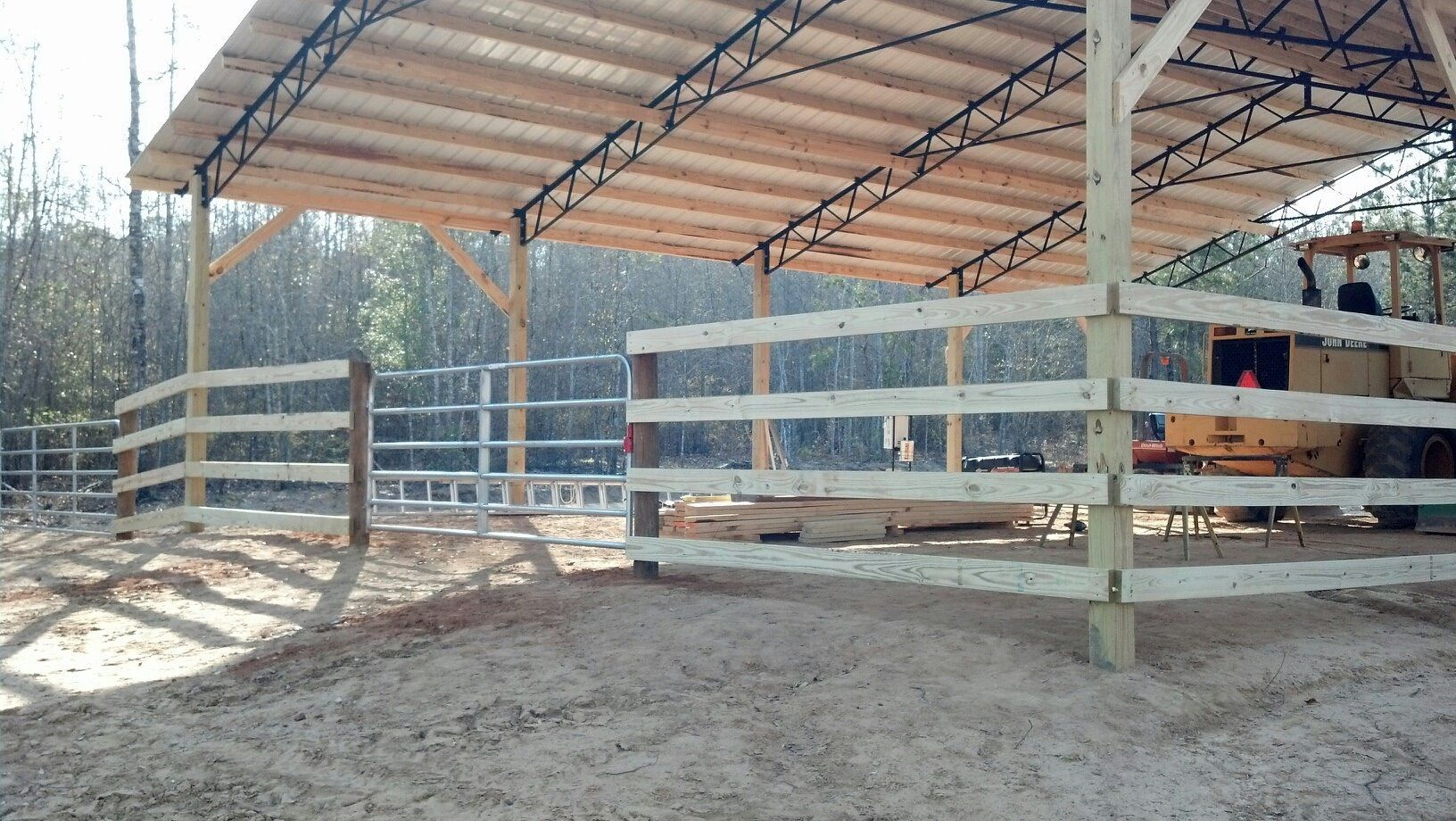 A horse stable with a wooden fence and a metal roof