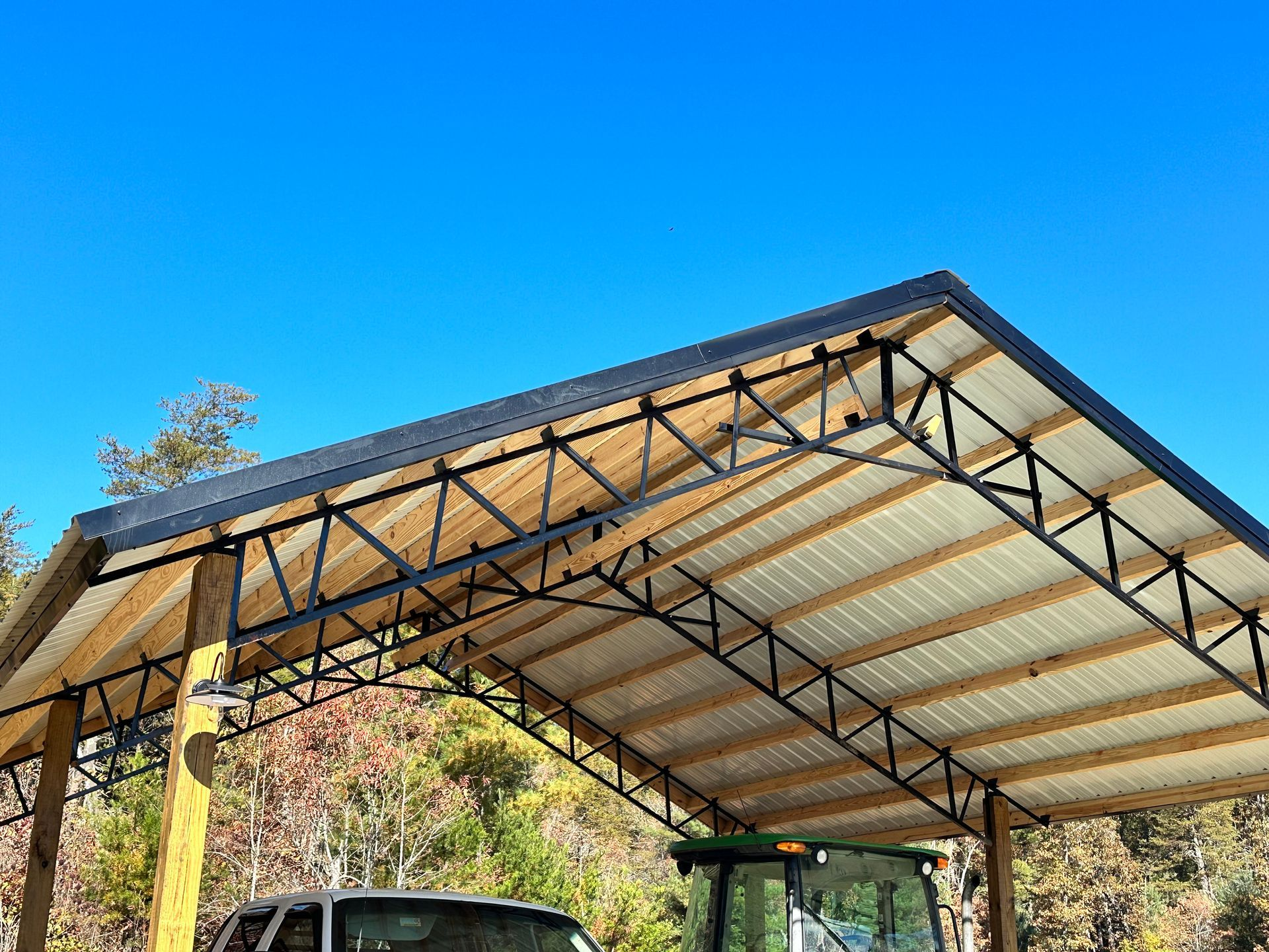 A tractor is parked under a carport with a blue sky in the background.
