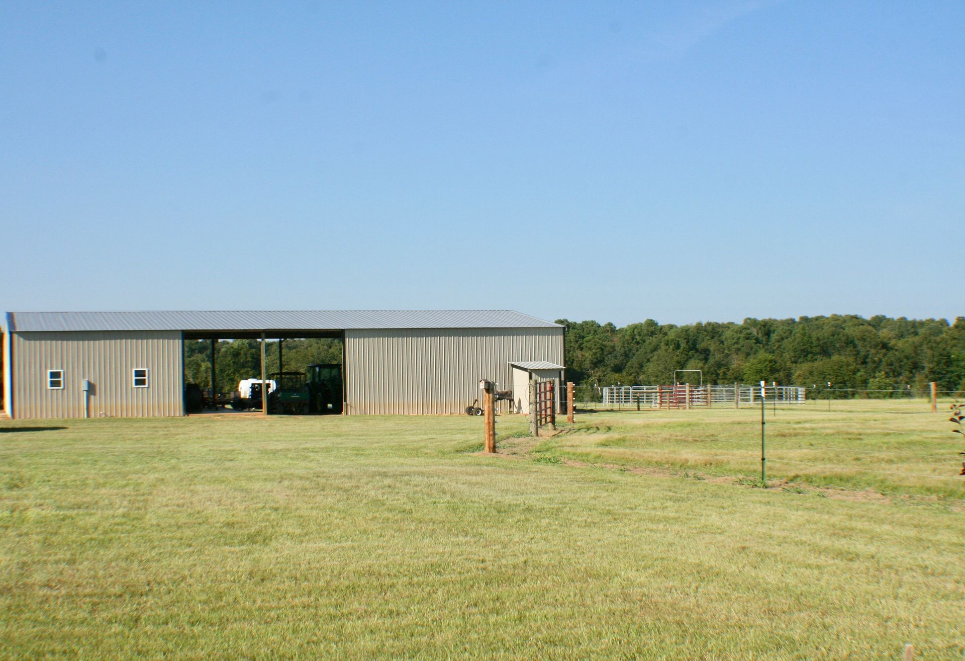 A large barn is sitting in the middle of a grassy field.