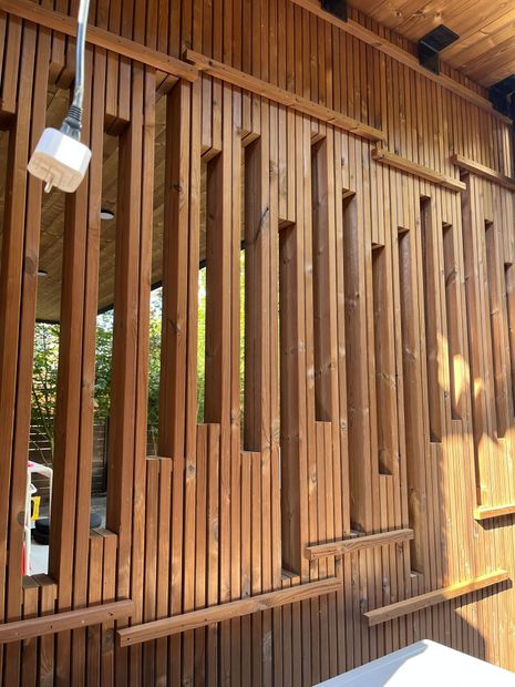 Wooden slat wall with narrow vertical openings and warm sunlight filtering through