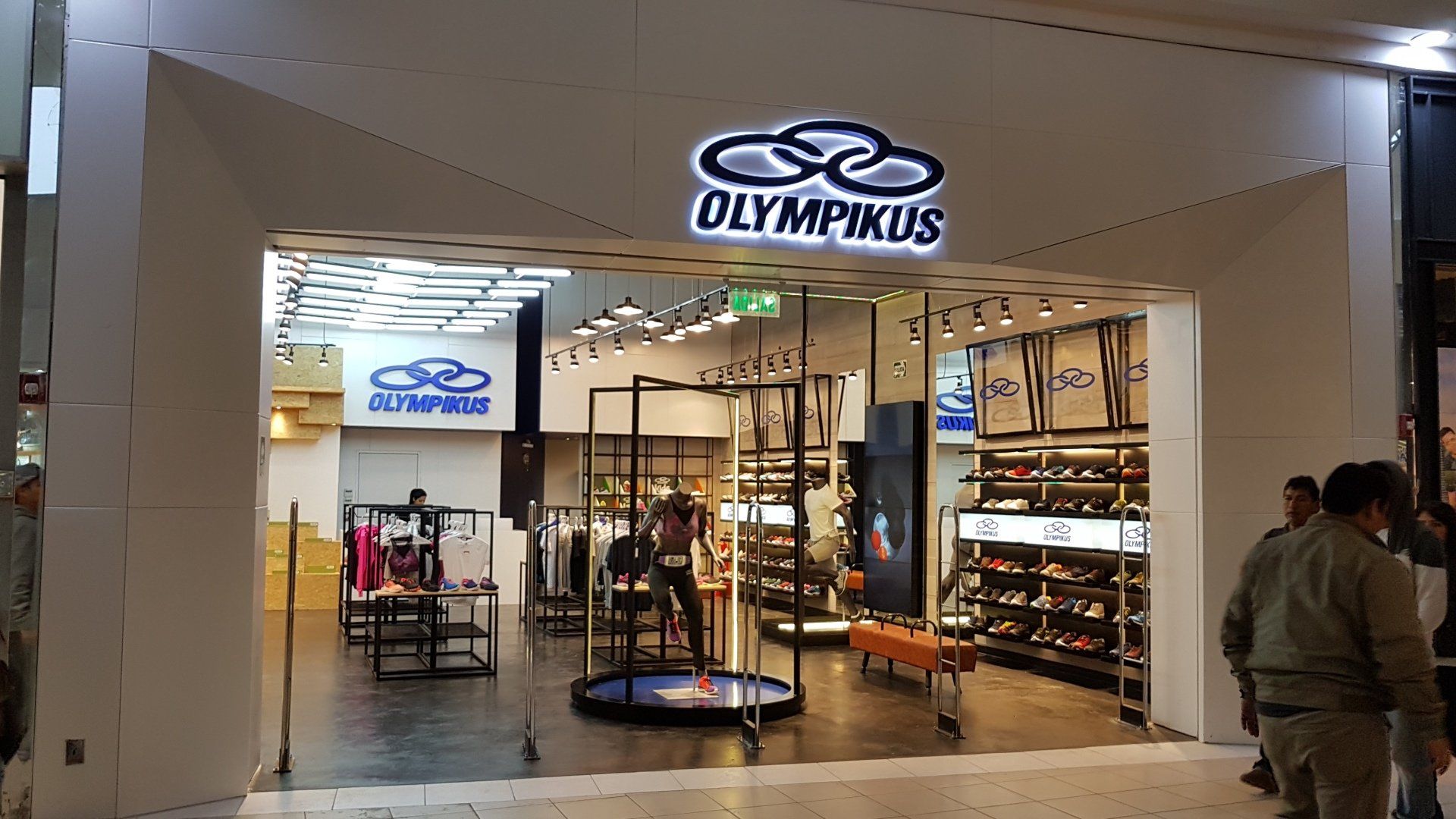 Un grupo de personas se encuentra afuera de una tienda llamada Olympikus.