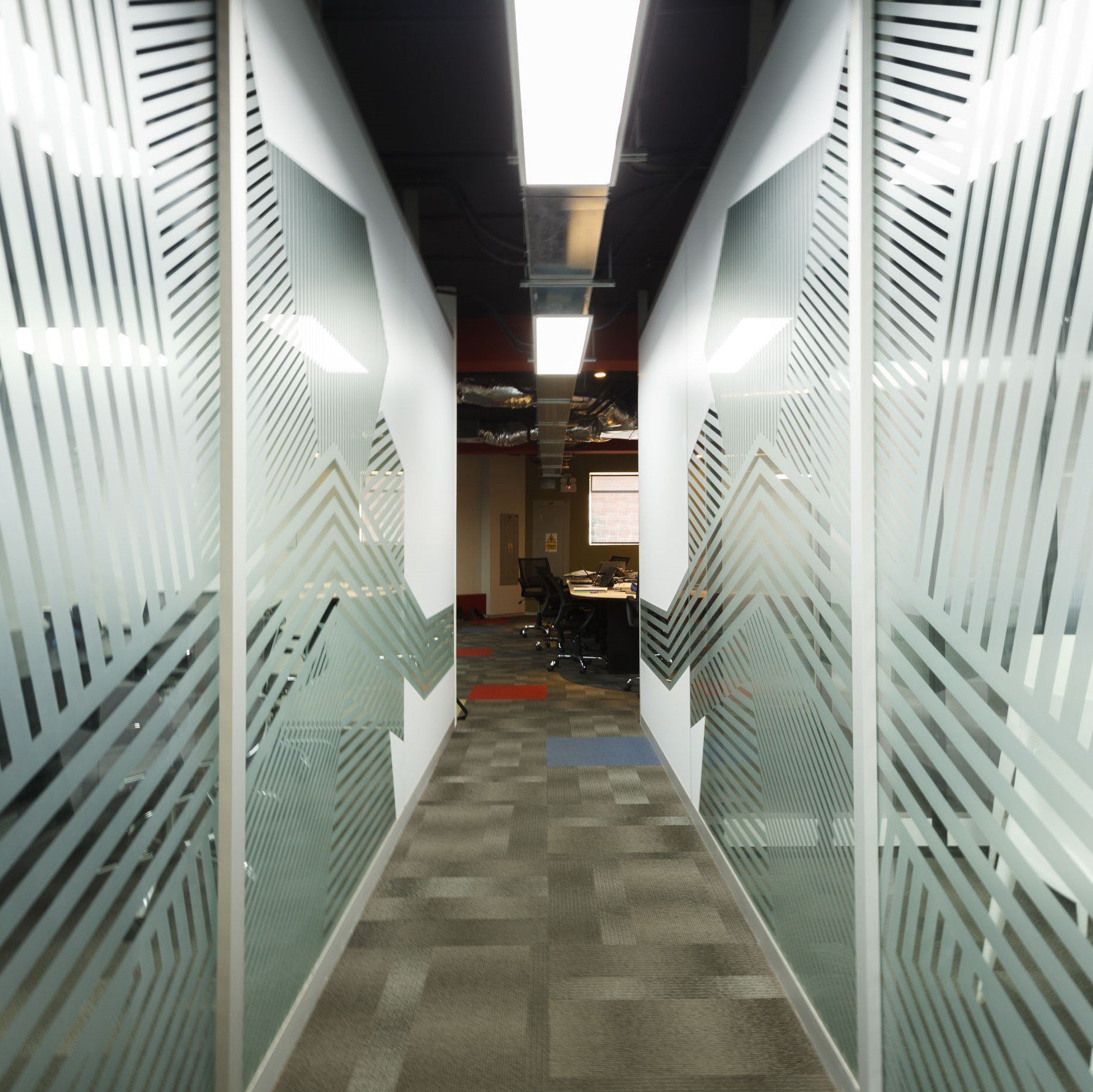 Un largo pasillo con un patrón geométrico en las paredes de cristal.