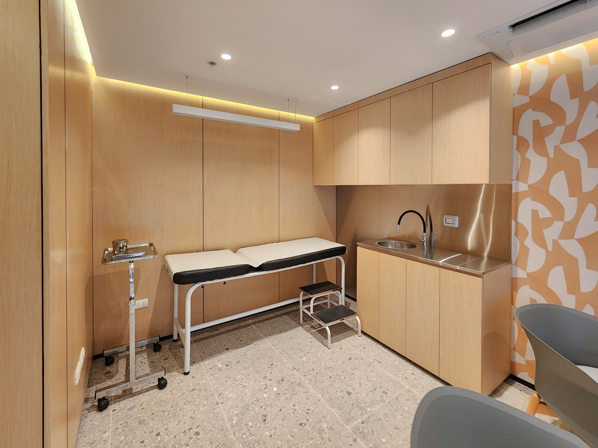 Impresión artística de un consultorio médico con una mesa de exploración y un lavabo.