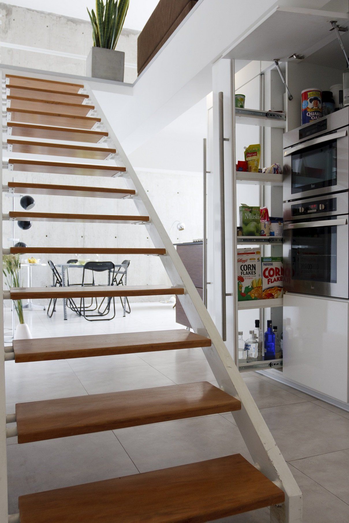Una escalera de madera que conduce a una cocina con una despensa detrás de ella.