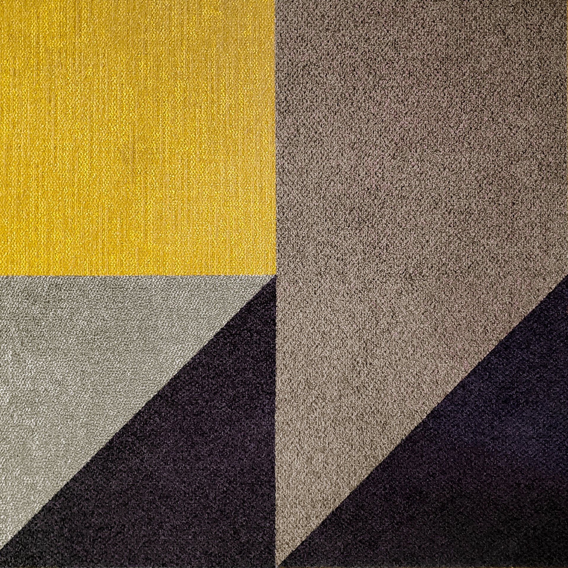 Un primer plano de una alfombra amarilla, gris y negra con un patrón geométrico.