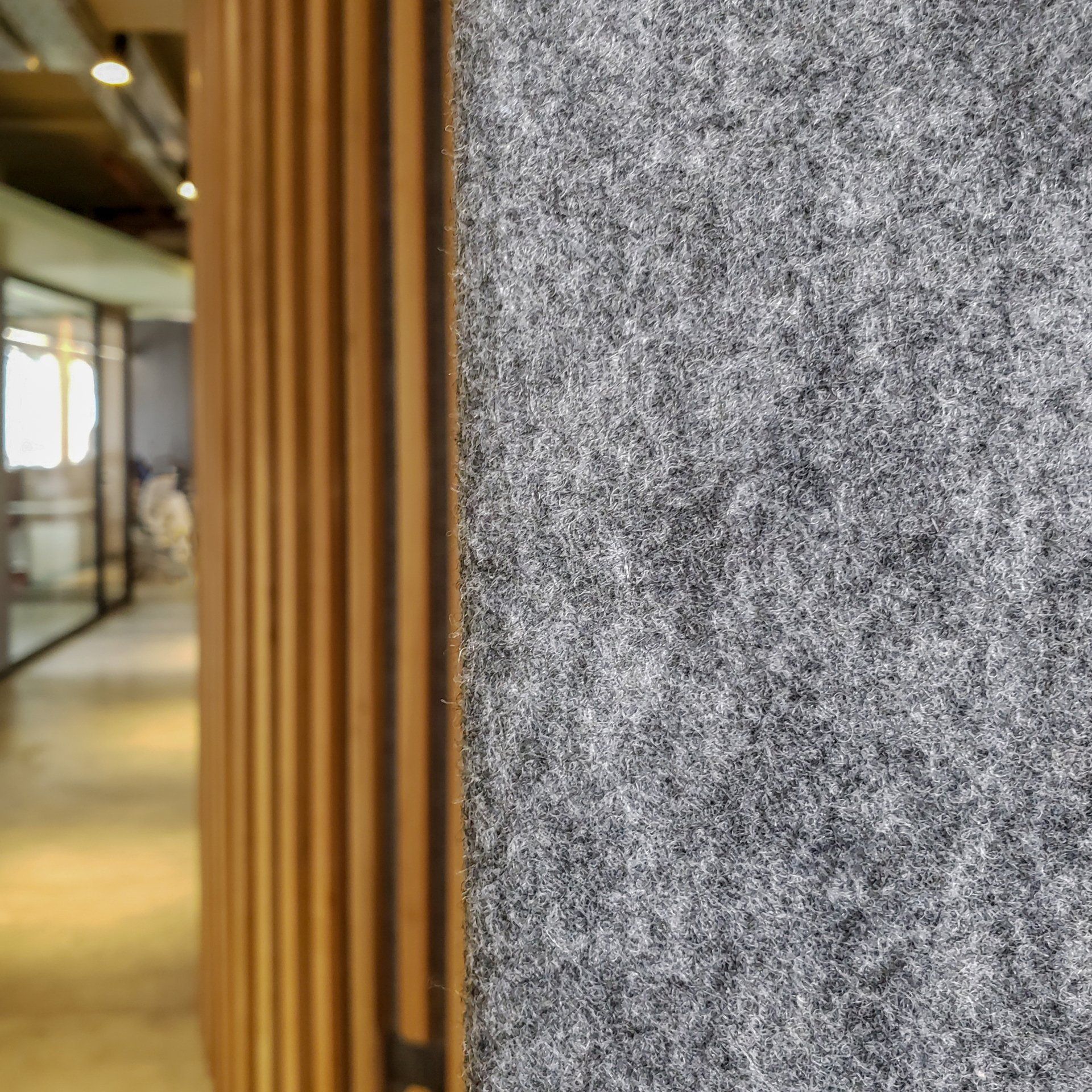 Un primer plano de una pared gris con listones de madera en un pasillo.